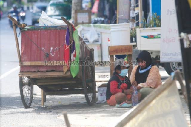 PERLU PERHATIAN: Seorang ibu dan anaknya beristirahat di samping gerobak yang menemani perjalanan mereka. Potret salah satu kehidupan keluarga yang terlihat di sekitar Jln A Yani, Kota Banjarbaru. | Foto: Muhammad Rifani/Radar Banjarmasin