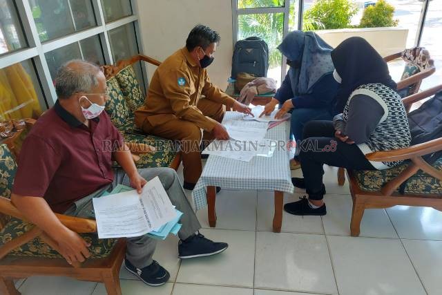 CEK BERKAS: Wakasek SMPN 7 Banjarmasin mengecek berkas persyaratan untuk pendaftaran di jalur perpindahan orang tua, kemarin (28/6). | FOTO: WAHYU RAMADHAN/RADAR BANJARMASIN