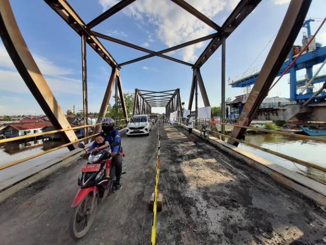 BAKAL DIBONGKAR: Pengendara melintas di Jembatan Lama Sungai Alalak, kemarin. Hampir rampungnya jembatan baru membuat jembatan lama mendesak dibongkar. \ FOTO: M OSCAR FRABY/RADAR BANJARMASIN