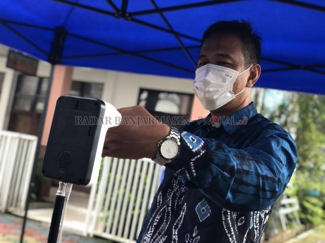 CEK SUHU: Kepala Sekolah SMP Negeri 1 Banjarbatu, Undi Sukarya mengecek fungsi alat pengukur suhu tubuh yang ditempatkan di bagian pintu masuk sekolah. Mayoritas sekolah mengklaim sudah siap memberlakukan PTM terbatas. | Foto: Muhammad Rifani/Radar Banjar