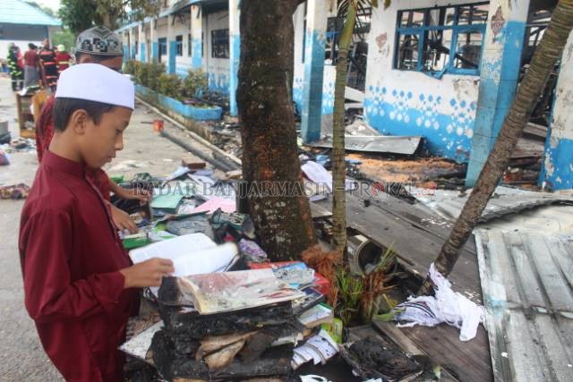 TINGGAL PUING: Seorang santri melihat kitab dan buku yang terbakar tak sempat diselamatkan. | FOTO: SUTRISNO/RADAR BANJARMASIN