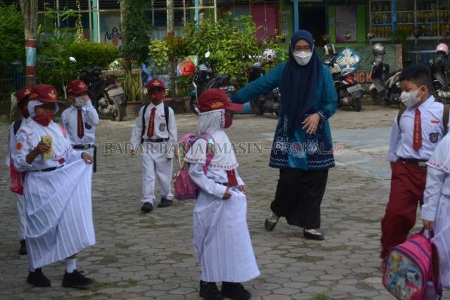 KEMBALI SEKOLAH: Sejak memasuki halaman sekolah, para guru sudah mengawasi anak didiknya untuk senantiasa menjaga jarak. | FOTO: WAHYU RAMADHAN/RADAR BANJARMASIN