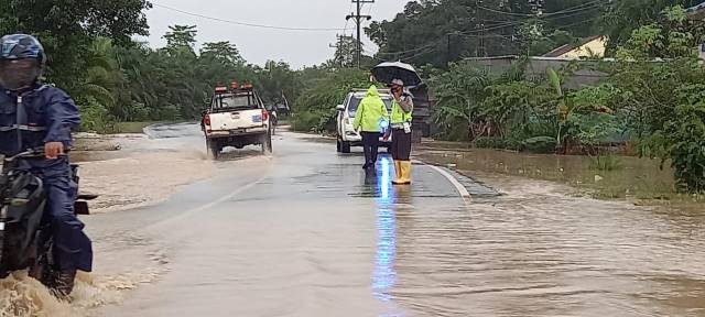 TERGENANG: Polisi berjaga di jalan Satui, meminta pengendara hati-hati.