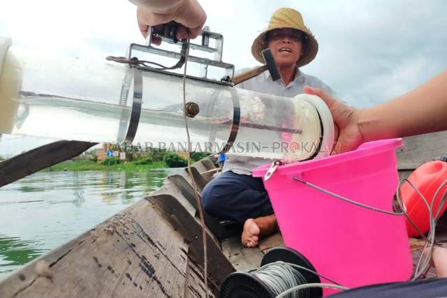 UNTUK PENELITIAN: Menaiki sampan, petugas lab DLH mengambil sampel air Sungai Martapura di kawasan Sungai Lulut. Di sini, airnya masih berwarna hijau. | Foto: WAHYU RAMADHAN/RADAR BANJARMASIN