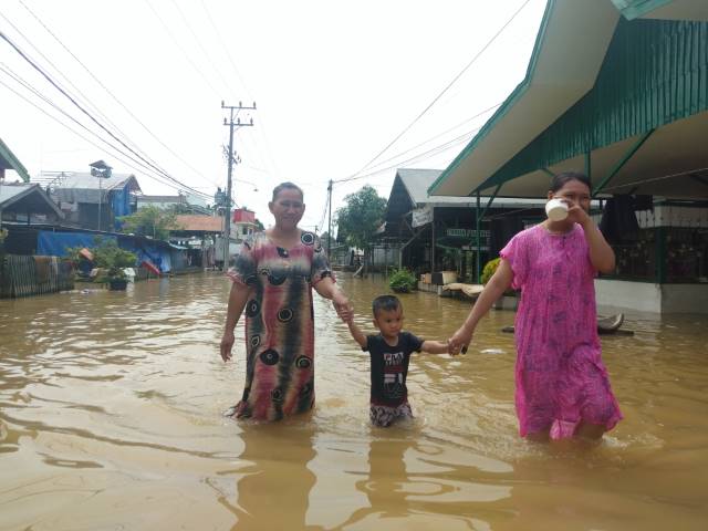 BANJIR: Seorang anak dituntut melewati banjir. Ini terjadi di Jalan Tengkarau, Kecamatan Barabai saat banjir besar di HST awal tahun lalu. | FOTO: JAMALUDDIN/RADAR BANJARMASIN