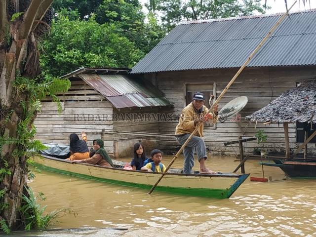 BERPERAHU: Warga melintasi banjir di Jorong Talut dengan perahu. Daerah tenggara Kalsel selalu menjadi langganan banjir. | FOTO: NORSALIM YAHYA/RADAR BANJARMASIN