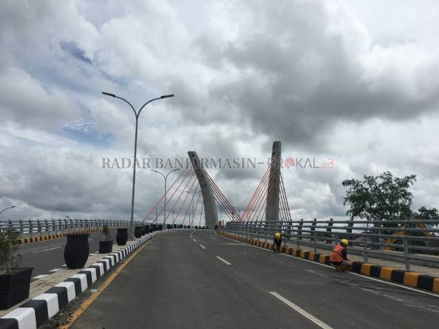 MASIH MENUNGGU: Pekerja mengecat trotoar jembatan, kemarin.  Meski diklaim sudah selesai, jembatan belum juga dibuka. | FOTO: M OSCAR FRABY/RADAR BANJARMASIN