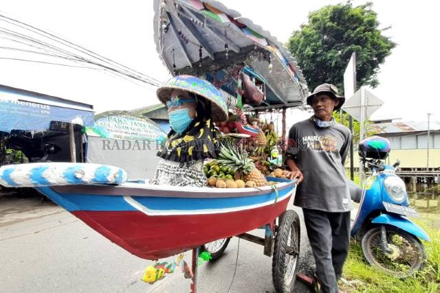 JUKUNG DORONG: Fahrul, 55 tahun, berpose di samping jukung darat kebanggaannya. Selama 20 tahun ia berdagang di Pasar Terapung. | FOTO: WAHYU RAMADHAN/RADAR BANJARMASIN