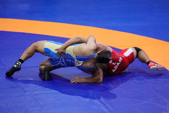 ADU BANTING: Aksi pegulat Kalsel Adam Wibowo (merah) saat menghadapi pegulat Jawa Barat Seni Kristian di babak perebutan medali perunggu yang berlangsung di GOR Hiad Sai, Merauke, Papua. | Foto M Idris / Radar Banjarmasin