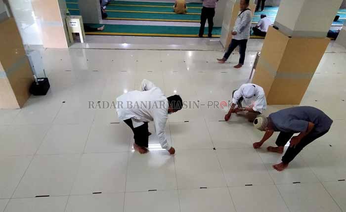 BEROPERASI PENUH: Petugas Masjid Al Jihad Banjarmasin mencabut stiker pembatas saf di bagian luar raung induk, Senin (18/10) siang. | Foto: Endang/Radar Banjarmasin