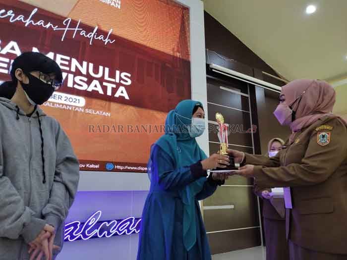 SELAMAT YA: Kepala Dispersip Kalsel Nurliani menyerahkan hadiah kepada Ratih Ayuningrum, pemenang pertama Lomba Cerpen Wisata Kalsel, kemarin.