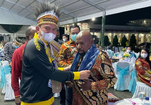 APRESIASI: Kadispora Kalsel, H Hermansyah mengalungkan kain Sasirangan kepada Gubernur Papua, Lukas Enembe pada acara Gala Dinner dan Baku Dapa Peparnas XVI 2021 Papua, Kamis (4/11) malam.