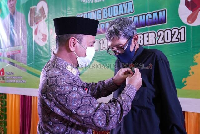 SETIA KEPADA SASTRA: Staf Ahli Gubernur Kalimantan Selatan Bidang Ekonomi dan Pembangunan, Faried Fakhmansyah (kiri) menyematkan lencana anugerah 30 tahun kesetiaan Setya Sastra Negeri kepada salah seorang sastrawan di Aruh Sastra Balangan, kemarin. | FOT