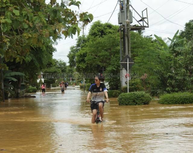 SANTAI: Warga melintasi Jalan Telaga Padawangan saat menerjang banjir di Kota Barabai Senin 15 November lalu. | FOTO: JAMALUDDIN/RADAR BANJARMASIN