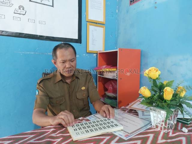 MENGINSPIRASI: Sabran (44) saat menunjukkan alat untuk mengajar berupa huruf braille di ruang kelasnya, Selasa (30/11). | FOTO: JAMALUDDIN/RADAR BANJARMASIN