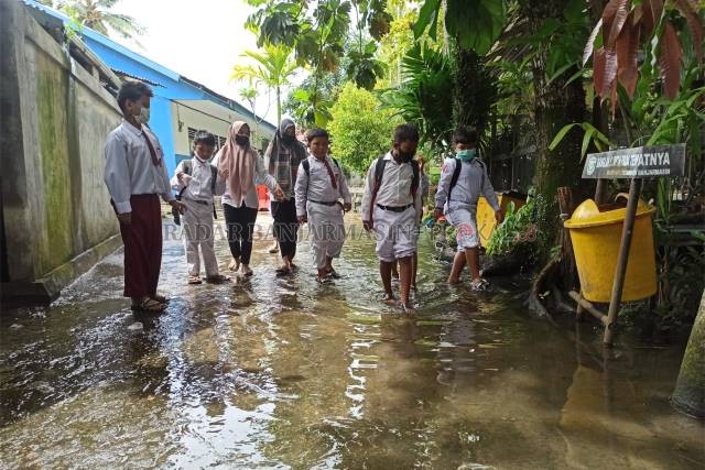 LEPAS SEPATU: Sejak kemarin, SDN Antasan Besar 7 memutuskan kembali belajar daring selama bangunan sekolah masih terendam. | FOTO: WAHYU RAMADHAN/RADAR BANJARMASIN