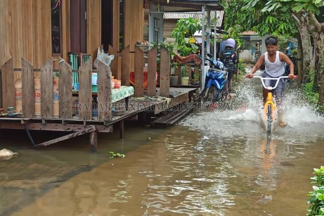 MAIN AIR: Bocah di Jalan Simpang Layang, Sungai Lulut, menjadikan genangan sebagai area bermain. | FOTO: WAHYU RAMADHAN/RADAR BANJARMASIN
