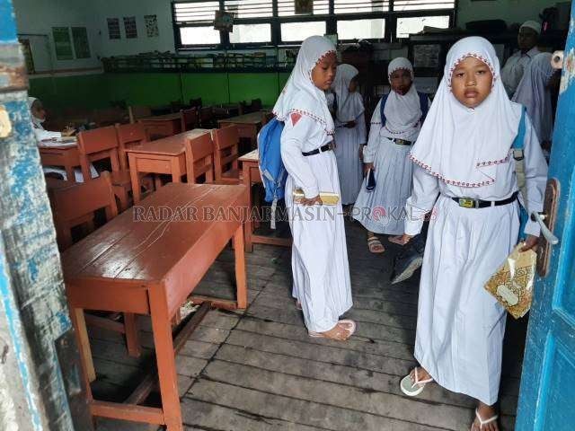JINJING: Selama banjir rob melanda Banjarmasin, siswi SDN Alalak Utara 1 belajar dengan mengenakan sandal jepit. Sepatu dijinjing pakai tangan. | FOTO: WAHYU RAMADHAN/RADAR BANJARMASIN