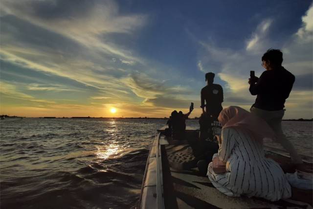 SILUET: Menikmati sunset tak harus ke bibir pantai atau ke puncak gunung, di muara sungai pun bisa. Foto diambil di Sungai Barito. | FOTO: WAHYU RAMADHAN/RADAR BANJARMASIN