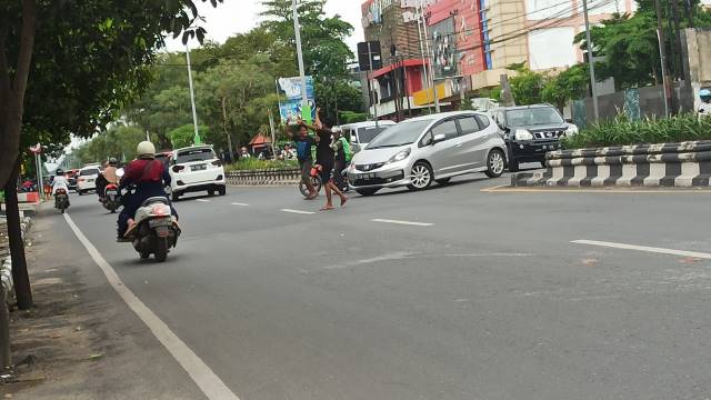 DIANGGAP MENGGANGGU: Para remaja mengatur lalu lintas saat beroperasi di u-turn di Jalan A Yani, Banjarbaru, kemarin. | FOTO: SUTRISNO/RADAR BANJARMASIN
