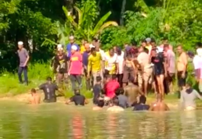 EVAKUASI: Warga Sungai Limas dibantu relawan mengevakuasi jenazah Haji Acut dari tepi kolam. (Foto: Capture Video Muhammad Akbar Radar Banjarmasin)