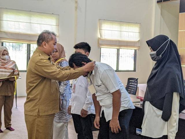 PELATIHAN : Kepala DPMPTSPTK Balangan, Abiji (kiri) mengalungkan tanda peserta kepada salah seorang peserta pelatihan. : FOTO WAHYUDI RADAR BANJARMASIN