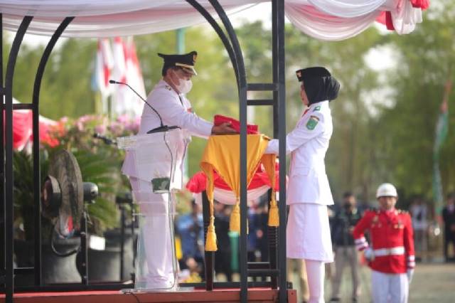 SAKRAL: Bupati Tanbu HM Zairullah Azhar menyerahkan bendera kepada Paskibra pada peringatan HUT ke-77 Kemerdekaan RI.