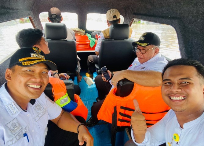 PENGABDIAN: Camat Rully Lesmana (kiri) saat naik speedboat menuju Paminggir.