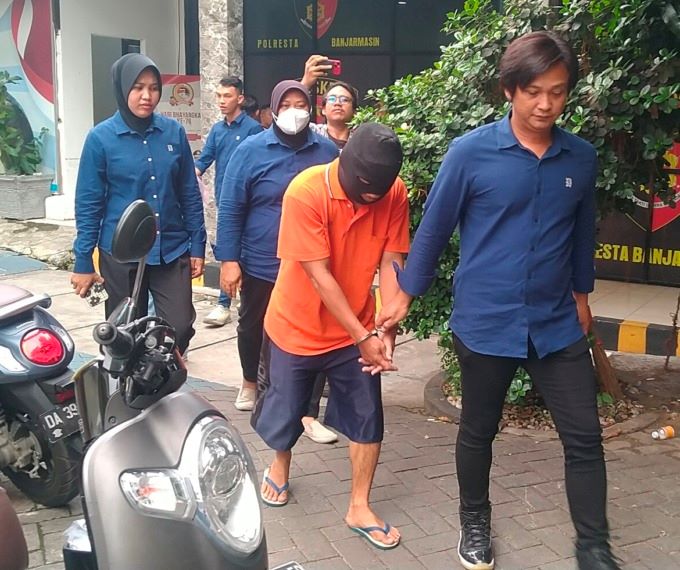 TANGAN TERBORGOL: Tersangka Y alias A dikawal penyidik Unit PPA Satreskrim Polresta  Banjarmasin. | FOTO: MAULANA/RADAR BANJARMASIN