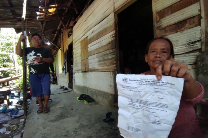 SEDIH: Sunarah, memperlihatkan surat perintah pengosongan lahan dan bangunan yang dilayangkan DKP3 melalui Satpol PP Banjarmasin. | FOTO: WAHYU RAMADHAN/RADAR BANJARMASIN