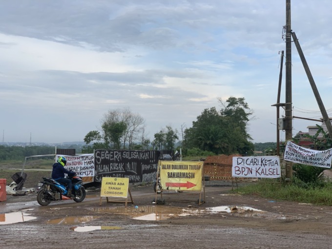 DI KM 171: Spanduk dan tulisan cat semprot bernada protes di jalan nasional yang terputus di Satui, Kabupaten Tanah Bumbu. | FOTO: ZULQARNAIN/RADAR BANJARMASIN