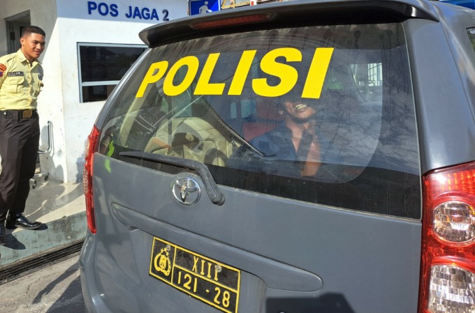 DIBAWA KE MAPOLSEK: Di balik kaca mobil polisi, lelaki berinisial PS ini masih bisa menyunggingkan senyum. Ia diringkus seusai nekat mengamuk di aula Kayuh Baimbai, Balai Kota Banjarmasin, (28/7). | FOTO: WAHYU RAMADHAN/RADAR BANJARMASIN