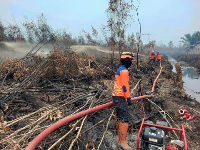 TERUS DISEMPROT: Petugas BPBD Banjarmasin terus melakukan pembasahan di lahan rawa sekitar Ring 1 Bandara. | FOTO: M FADLAN ZAKIRI/RADAR BANJARMASIN
