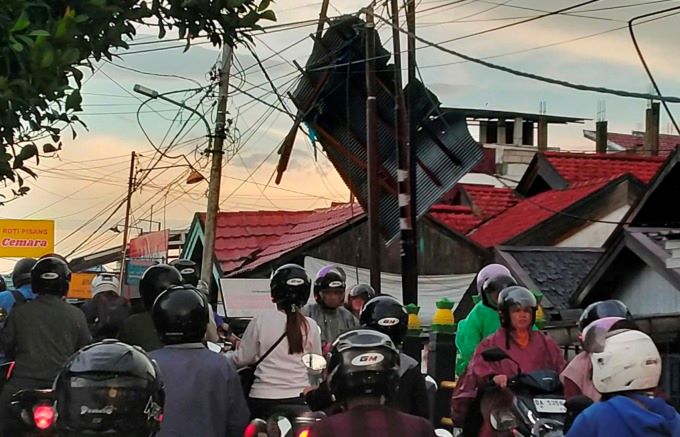 NYANGKUT: Atap Pasar Cemara terbang ditiup angin dan tersangkut di jaringan kabel di kawasan Sungai Miai, Senin (16/10) sore. | FOTO: MAULANA/RADAR BANJARMASIN