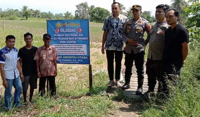 DILARANG: Kapolsek Amuntai Utara Ipda Fannan, dan warga melaksanakan pemasangan spanduk stop Illegal Fishing. ((Foto: Akbar/Radar Banjarmasin).)