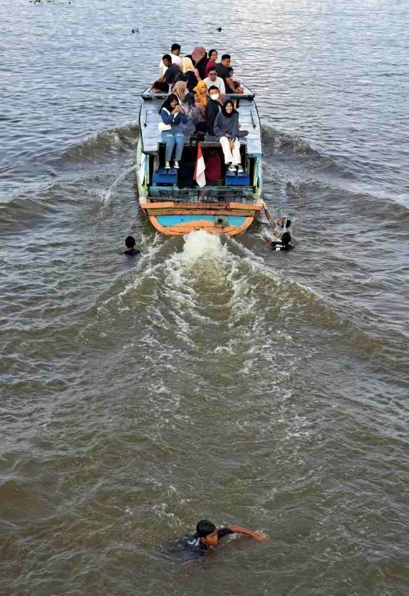 PERMAINAN BERBAHAYA: Anak-anak berenang di Sungai Martapura dan mencegat kelotok wisata. | FOTO: WAHYU RAMADHAN/RADAR BANJARMASIN