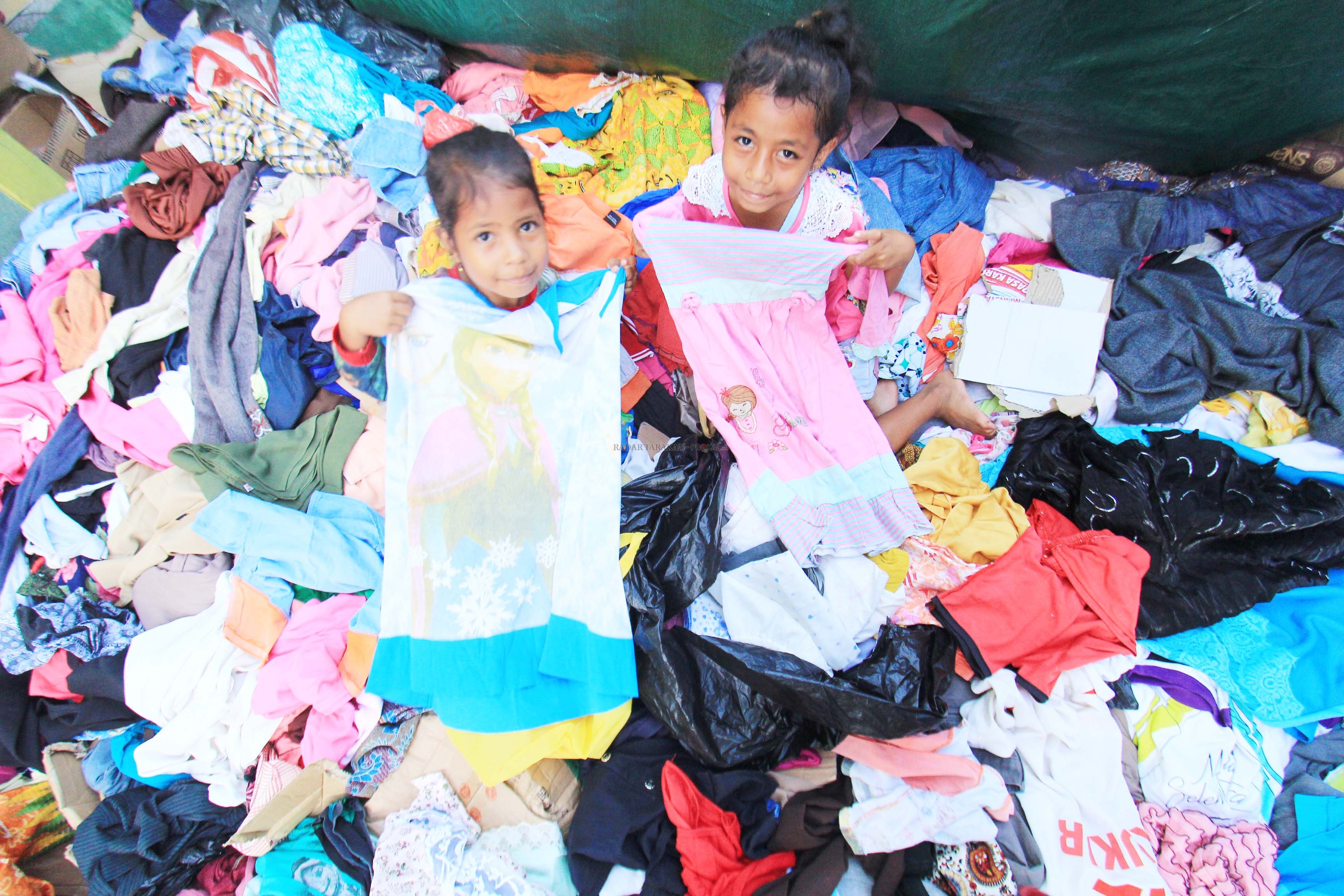 CARI YANG PAS: Dua anak sedang memilih baju yang disumbangkan masyarakat di posko tanggap darurat di Masjid Besar At-Taqwa, kemarin (22/1). Foto bawah, warga mengumpulkan sisa kebakaran.