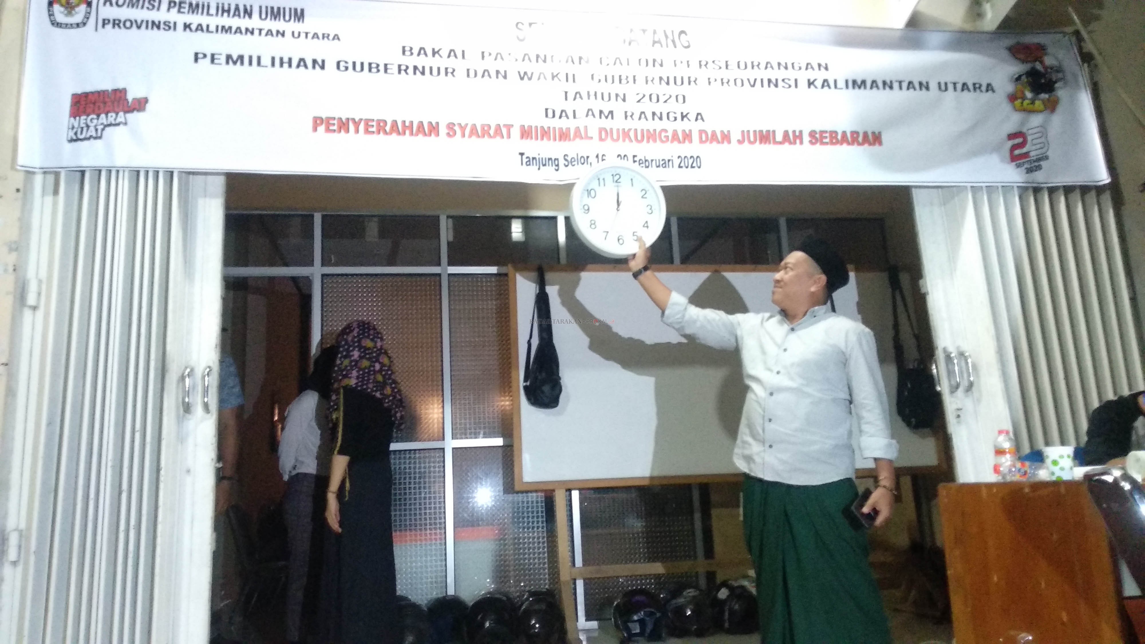 MENUNGGU BAKAL CALON: Ketua KPU Kaltara Suryanata Al Islami memegang jam dinding yang menunjukkan pukul 24.00 WITA di depan Sekretariat KPU Kaltara di Tanjung Selor, tadi malam. Hingga penutupan penyerahan syarat dukungan perseorangan tak ada lagi bakal c