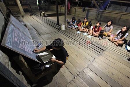 PERJUANGAN: Sri Tiawati atau Sukhet saat mengajar anak didiknya di pedalaman Semeriot, Sekatak, Bulungan, Sabtu (14/3) malam. FOTO: RACHMAD RHOMADHANI/RADAR TARAKAN
