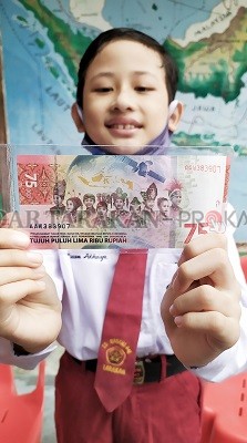 ANAK SPESIAL: Muhammad Izam Athaya, bocah kelas VI SDN 041 Tarakan memegang UPK 75 Tahun RI yang desainnya memuat gambar dirinya berpakaian adat Tidung, kemarin (18/8)./IFRANSYAH/RADAR TARAKAN