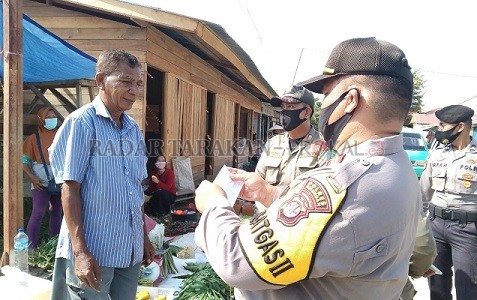 BELUM DITAATI: Protokol kesehatan masih diabaikan. Tampak petugas gabungan memberikan masker kepada salah satu pedagang pasar yang tidak menggunakan masker./PIJAI PASARIJA/RADAR KALTARA