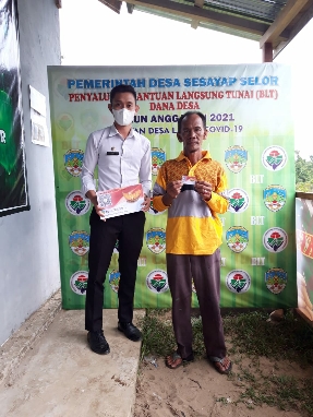 SIMBOLIS: Plt Kepala Desa Sesayap Selor Indra Hatari saat memberikan kartu BLT untuk memudahkan warga penerima PKM, Rabu (7/4). RIKO / RADAR TARAKAN