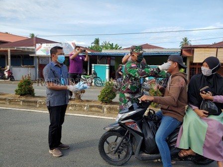 SALING MENGUATKAN DI TENGAH PANDEMI: H. Nuwardi Pakki (kiri), salah satu tokoh masyarakat Sebatik, Nunukan, Kaltara turun langsung membagikan masker kepada warga di Sebatik beberapa waktu lalu. FOTO: SATGAS COVID-19 SEBATIK