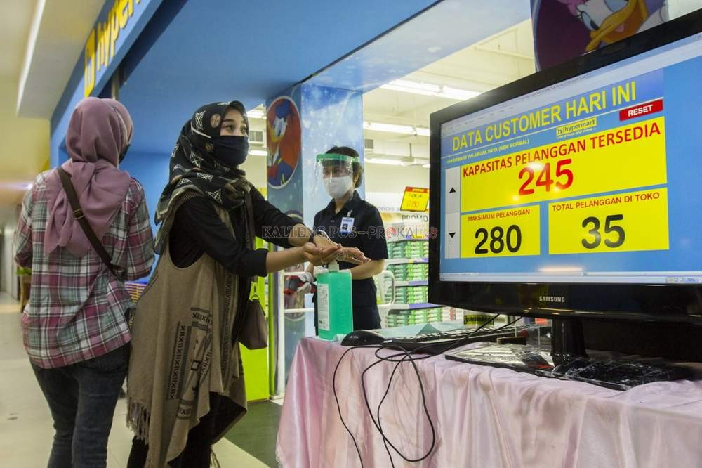 DEMI KENYAMANAN PENGUNJUNG: Monitor yang menunjukkan jumlah pengunjung terpampang di pintu masuk, kemarin (16/6). Hand sanitizer juga disiapkan bagi pengunjung sebelum masuk berbelanja. AGUS PRAMONO/KALTENG POS