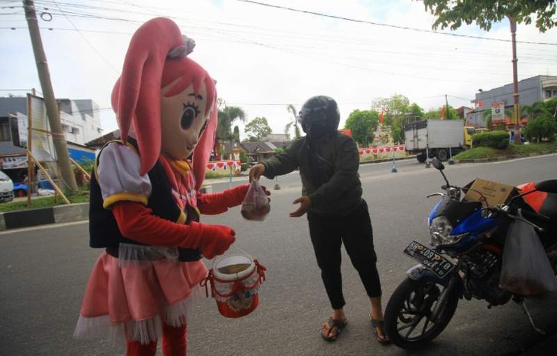 BERJIWA SOSIAL: Foto kiri, dr Muhamad Ridwan membagikan paket makanan siap saji kepada warga yang mengenakan kostum badut. Foto kanan, dr Muhamad Ridwan ketika memeriksa kesehatan warga di salah satu puskesmas di Palangka Raya sebelum pandemi Covid-19. DE