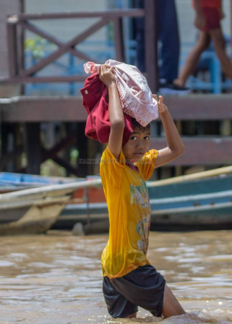 HINDARI SERAGAM BASAH: Salah satu murid SDN 1 Kameloh Baru melepas seragam sekolah agar terhindar dari air ketika di sekolah, Kamis (15/9).
