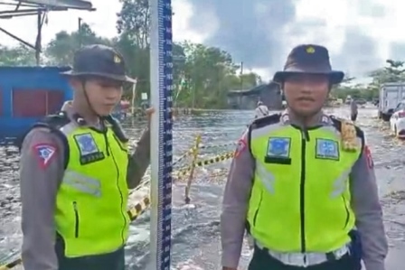 Anggota Satlantas Polres Pulang Pisau saat menginformasikan kondisi arus lalu lintas arah Jembatan Tumbang Nusa, Kecamatan Jabiren Raya Kabupaten Pulang Pisau yang terendam air, Rabu (23/11/2022). (FOTO IST)