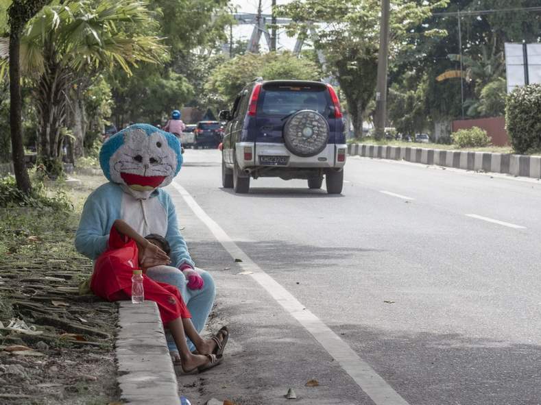 FENOMENA BADUT JALANAN: Seorang badut jalanan dengan karakter kartun doraemon saat duduk di Jalan A Yani, Palangka Raya, Jumat (20/1).