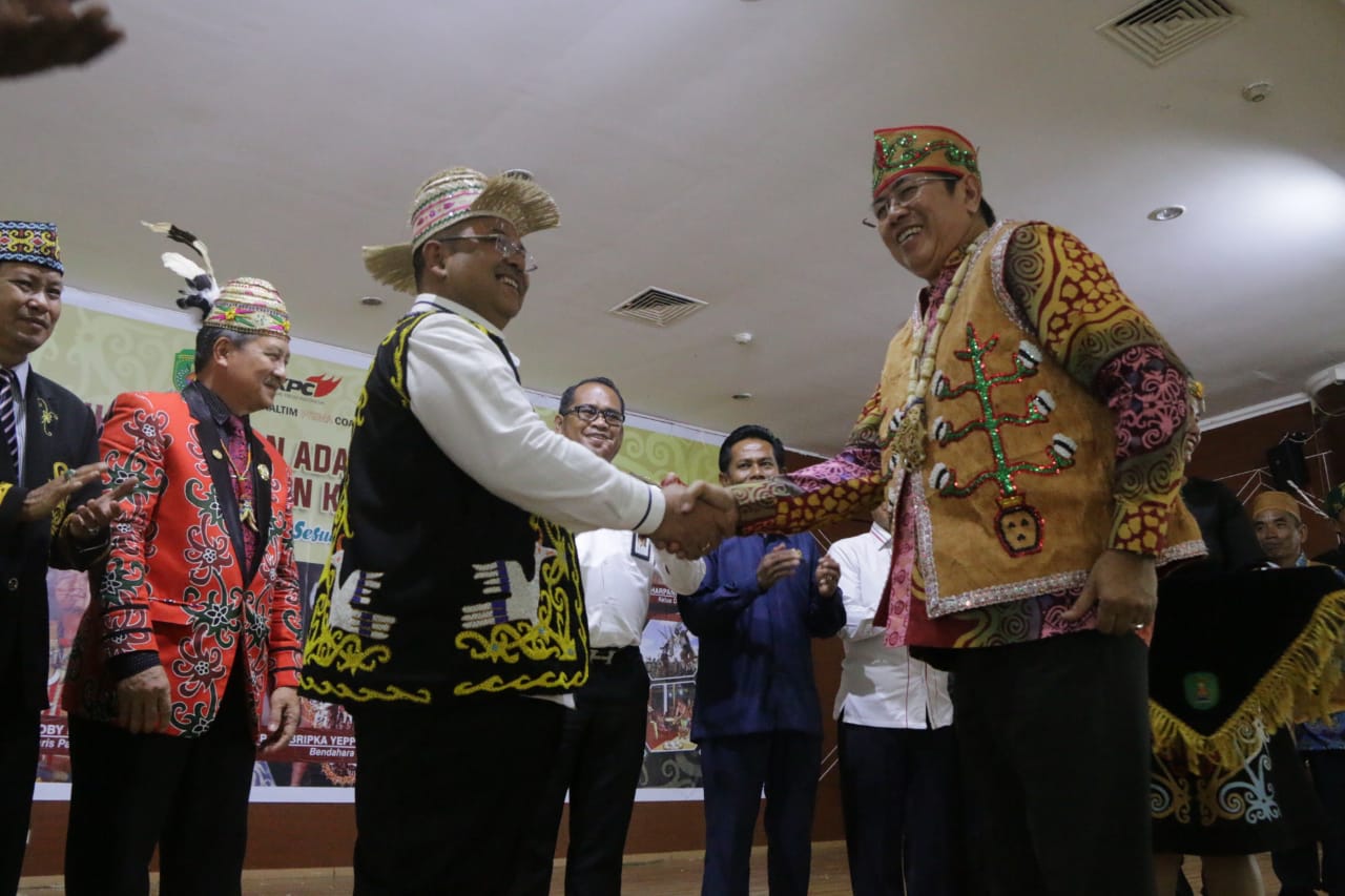 Bupati Kutim H Ismunandar mengenakan pakaian adat kepada pengurus DAD Kutim, di ruang Akasia GSG Pusat Perkantoran Pemkab Kutim. (Foto: Wak Hedir Humas)