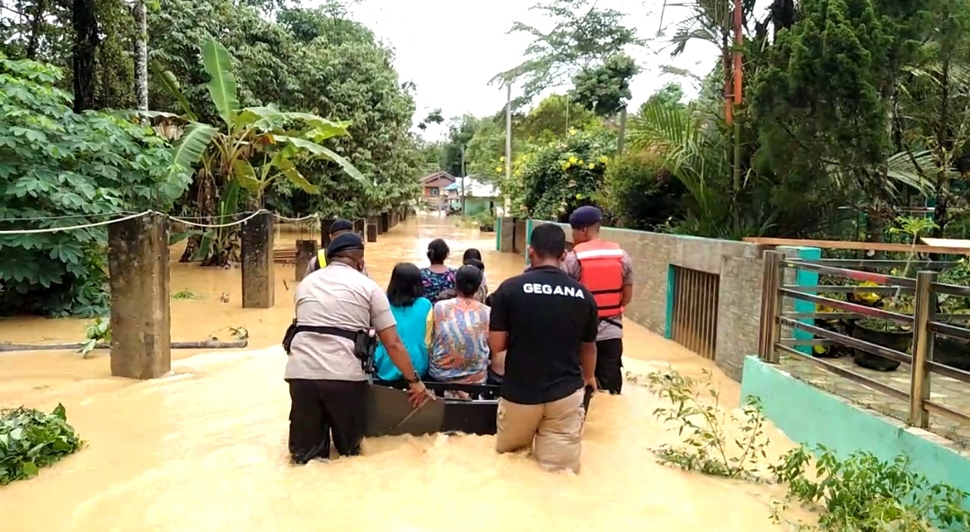 Anggota Brimob Polda Kaltim mengevakuasi anak-anak dan ibu tua yang terjebak banjir.